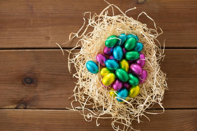 Photo chocolate eggs in foil wrappers in straw nest