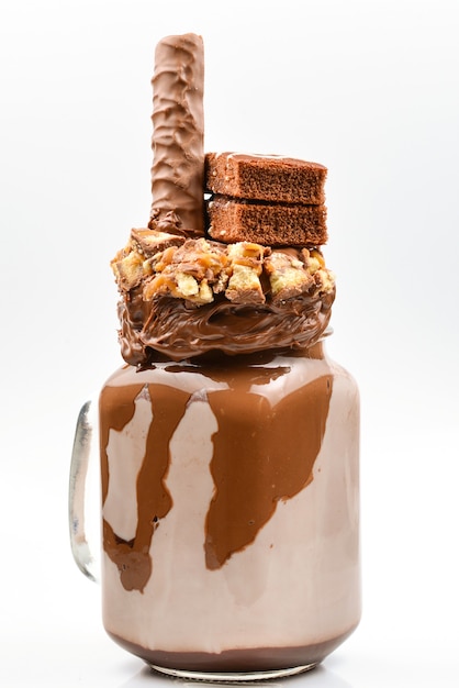 Chocolate extreme milkshake with brownie cake, chocolate paste and sweets. Crazy freakshake food trend. Copy space