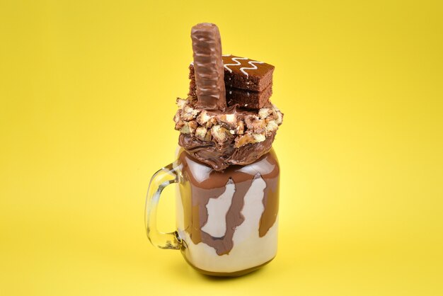 Chocolate extreme milkshake with brownie cake, chocolate paste and sweets. Crazy freakshake food trend. Copy space