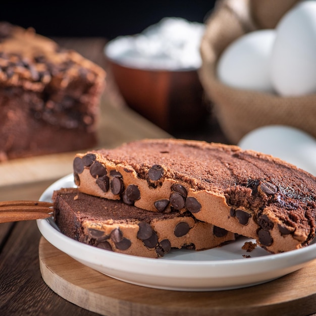 Photo chocolate flavor taiwanese traditional sponge cake taiwanese castella kasutera on a wooden tray background table with ingredients close up