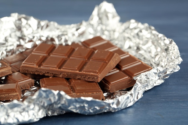 Chocolate in foil on wooden table closeup