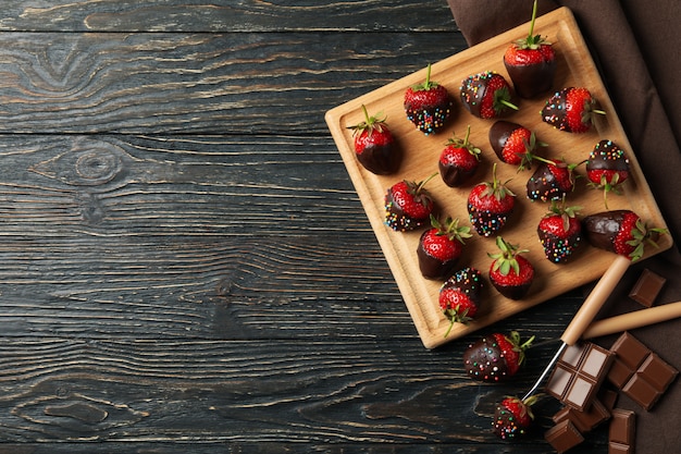 Chocolate fondue. Strawberry in chocolate on wooden background, top view