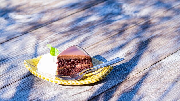 Chocolate fudge cake serve with cream on vintage wooden table