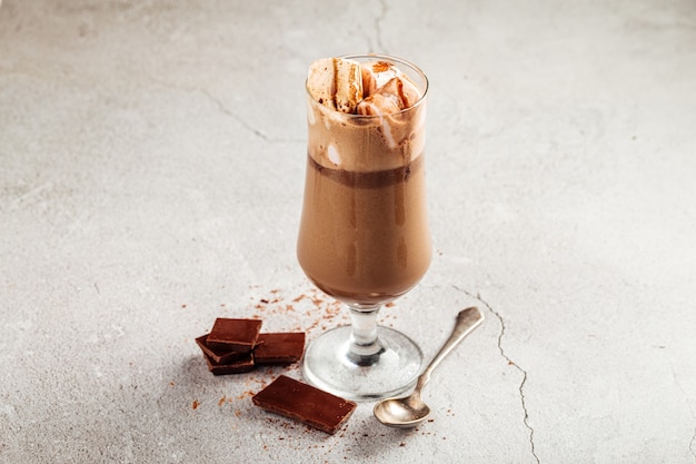 Caffè al cioccolato glace in un bicchiere su sfondo di cemento