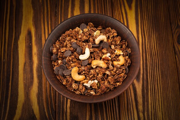 Chocolate granola cereal with nuts in a bowl on a wooden