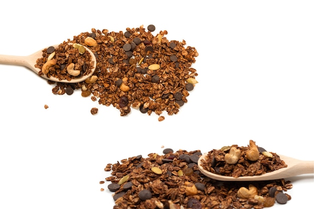 Chocolate granola cereal with nuts in a wooden spoon. Isolated on white bacckground.