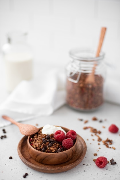 Chocolate granola with greek yogurt and raspberries in a wooden bowl, close-up