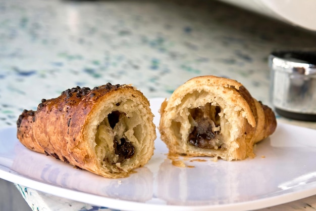 Chocolate hazelnut croissant halved or divided in two on white plate bread food