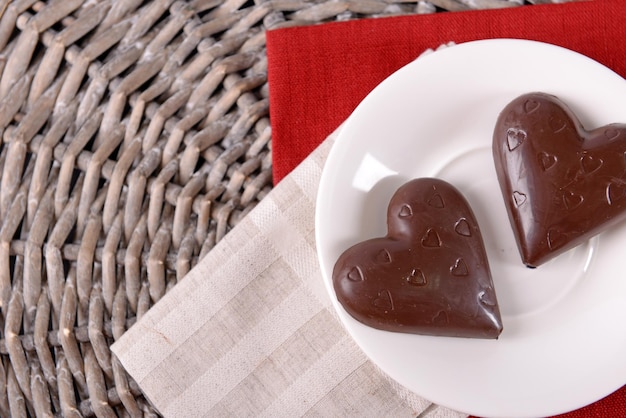 Chocolate heart shaped candies on sticks in white plate, closeup