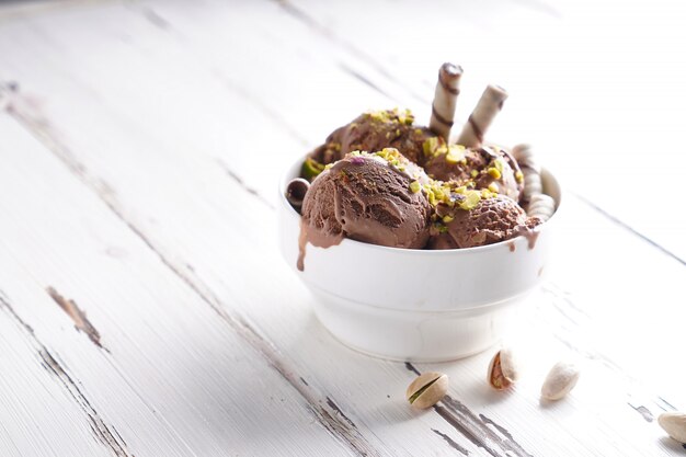 Foto palle di gelato al cioccolato con pistacchio e biscotti in una ciotola bianca