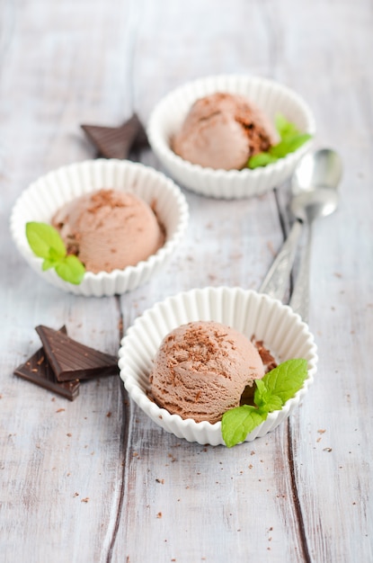 Chocolate ice cream in a white bowls on a wooden table.