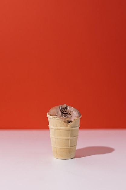 赤い背景のワッフルカップにチョコレートアイスクリームベジタリアン乳製品無料の滴ったお菓子
