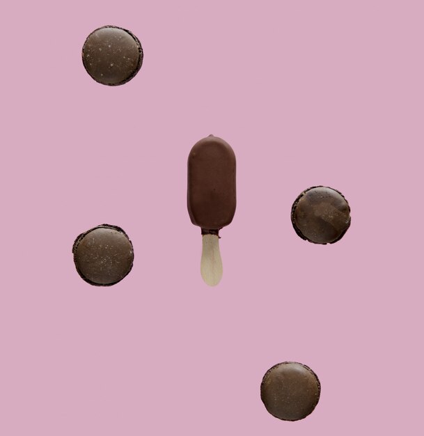 Chocolate ice lolly and french macrons on pink background. 