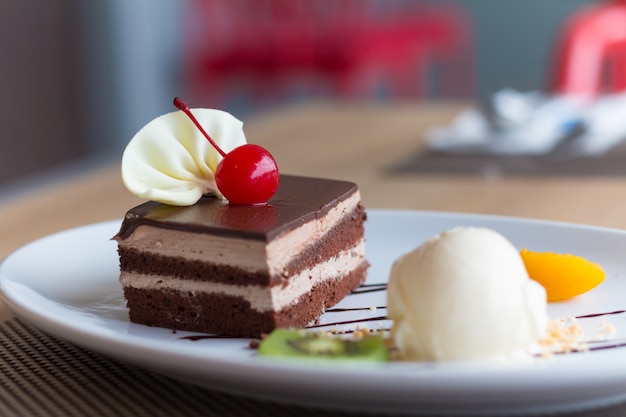 Chocolate layer cake and vanilla ice cream with fresh fruit and cherry