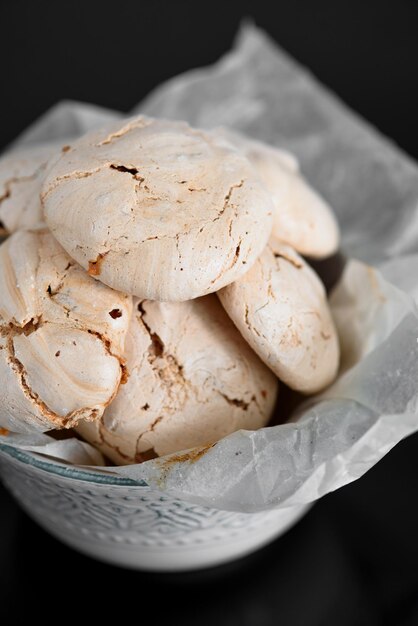 Chocolate meringue lies on a black table Meringue in a bowl Glossy black table