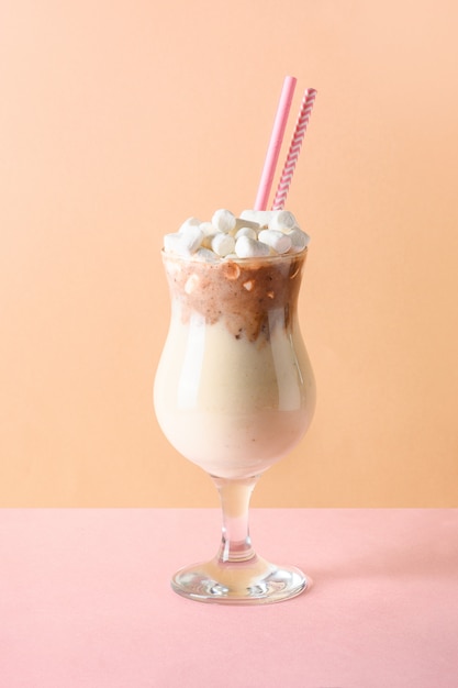 Chocolate milkshake garnish marshmallow on pink and beige paper.