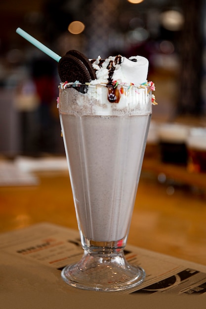 Chocolate milkshake with whipped cream and cookies on a table in a cafe vertical photo