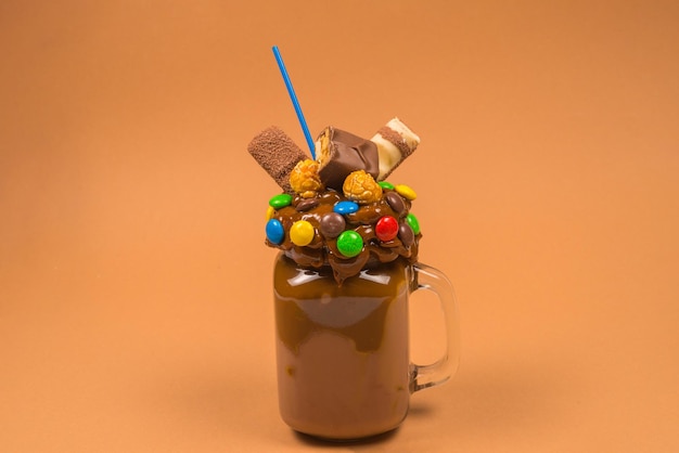 Шоколадный молочный коктейль со взбитыми сливками, печеньем, вафлями, подается в стеклянной банке. Сладкий коктейль «Фрик или сумасшедший». Пространство для текста или дизайна.