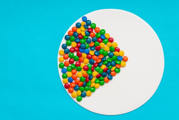 Chocolate moons of multiple colors on a blue background Colorful background made with chocolate candies of various colors