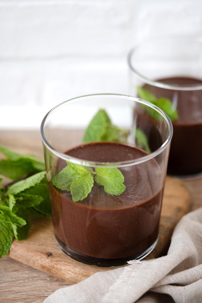 Chocolate mousse dessert garnished with mint leaf on wooden table