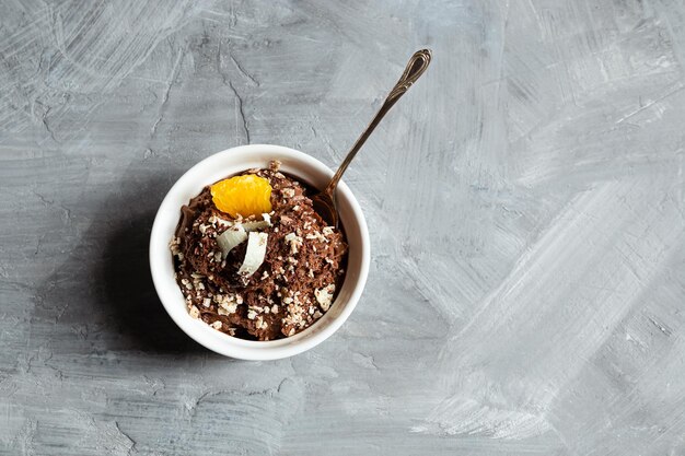 Chocolate mousse garnished with a tangerine wedge and white chocolate shavings in white bowl