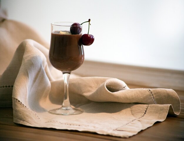 Chocolate mousse sauce in glass with cherries on wooden table Rustic style delicious chai latte