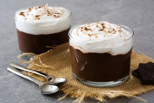 Chocolate mousse with cream in glass on gray