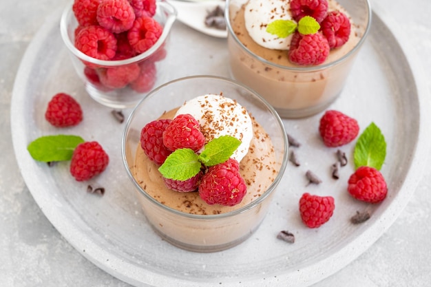 Chocolate mousse with whipped cream and fresh raspberries in a glass Copy space