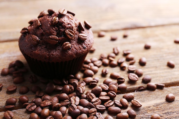 Photo chocolate muffin and coffee grains on wooden background