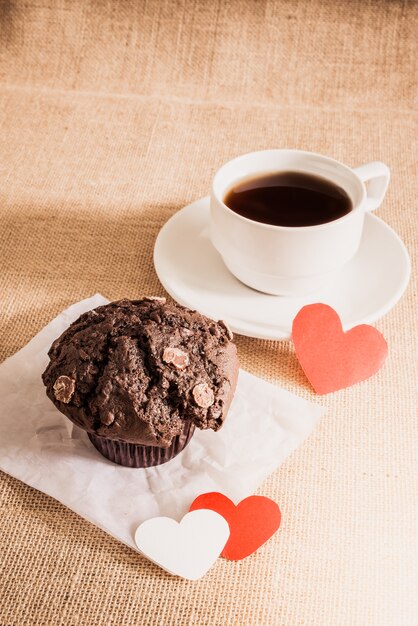 Muffin al cioccolato e caffè e cuori su trame di sacco