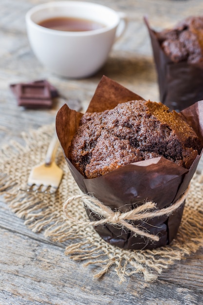 Muffin al cioccolato e una tazza di caffè su una superficie di legno.