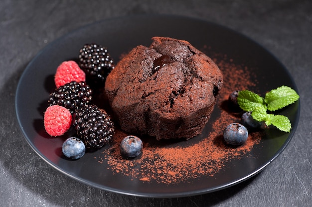 Chocolate muffin with berries on slate background