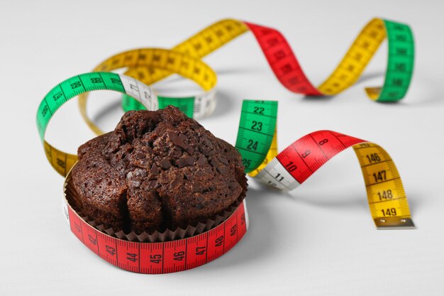 Chocolate muffin with centimeter on white background