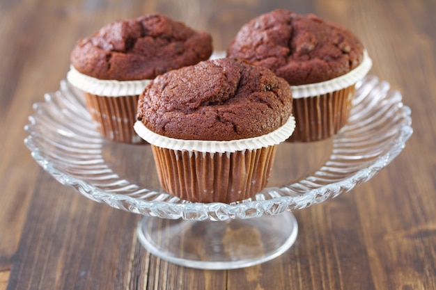 Chocolate muffins on dish on brown wooden background