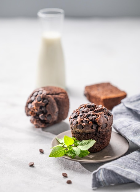 Photo chocolate muffins on a white plate with mint on a light background with milk the concept of healthy homemade baked for breakfast