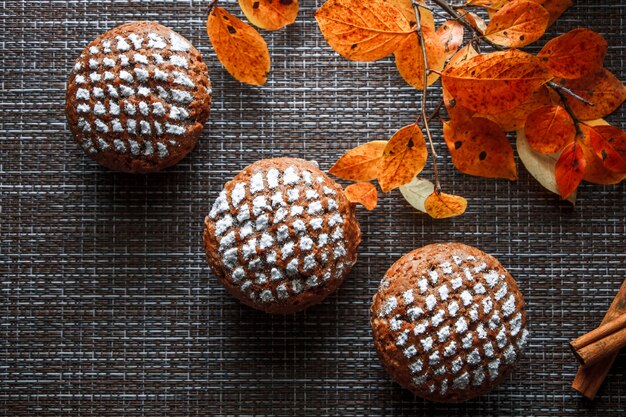 Muffin al cioccolato con ripieno di mele su uno sfondo di foglie di autunno e cannella