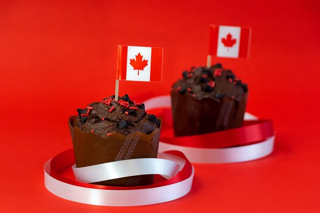 Chocolate muffins with canadian flags decorated with ribbons on red background