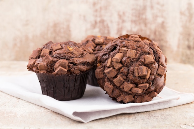 Chocolate muffins with chocolate on rustic wooden table