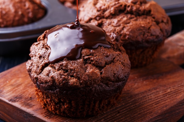 Chocolate muffins with chocolate syrup on dark