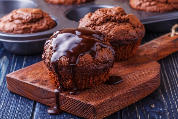 Chocolate muffins with chocolate syrup on dark