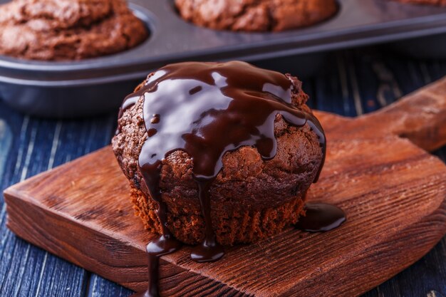 Muffin al cioccolato con sciroppo di cioccolato su fondo scuro