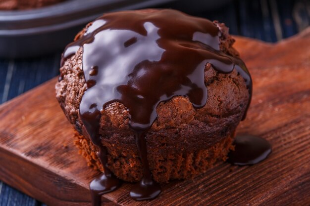 Muffin al cioccolato con sciroppo di cioccolato su fondo scuro