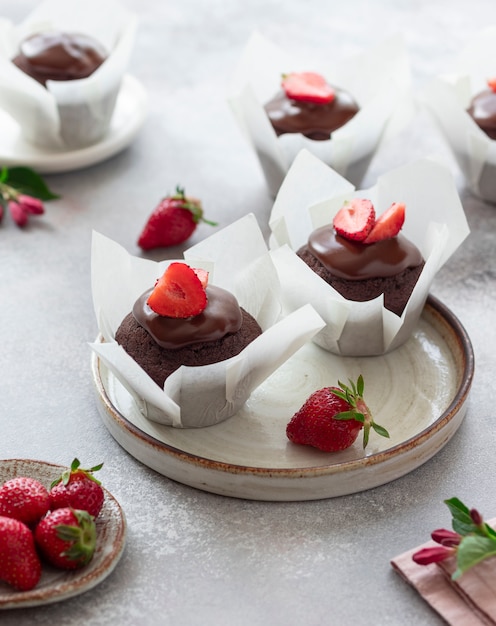 Chocolate muffins with chocolate syrup and fresh strawberries