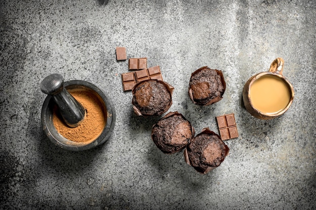 Chocolate muffins with coffee and cocoa on rustic table.