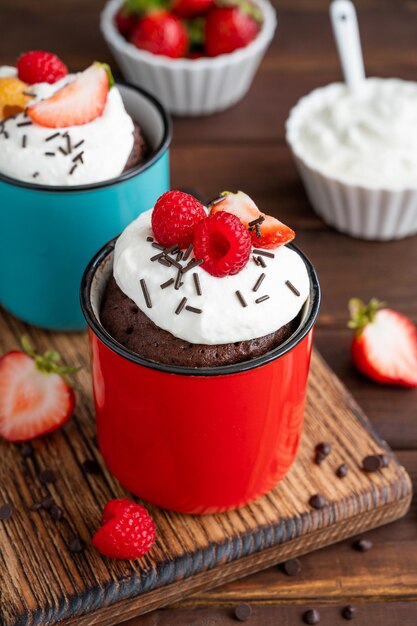 Chocolate mug cake with whipped cream and fresh berries Cupcake cooked in the microwave