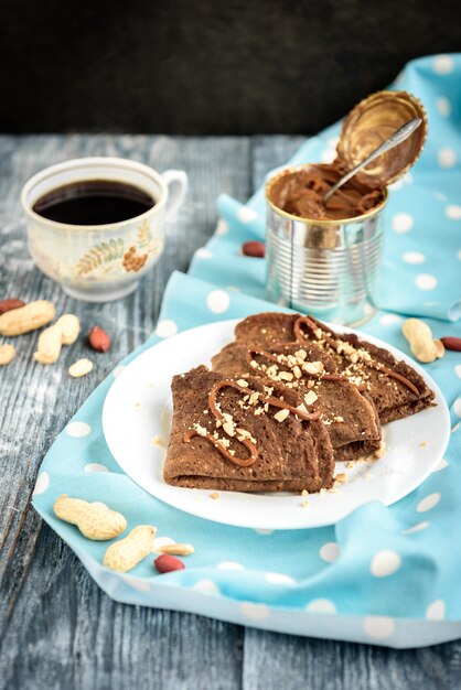 Chocolate oat pancakes with caramel and nuts on grey wooden table.