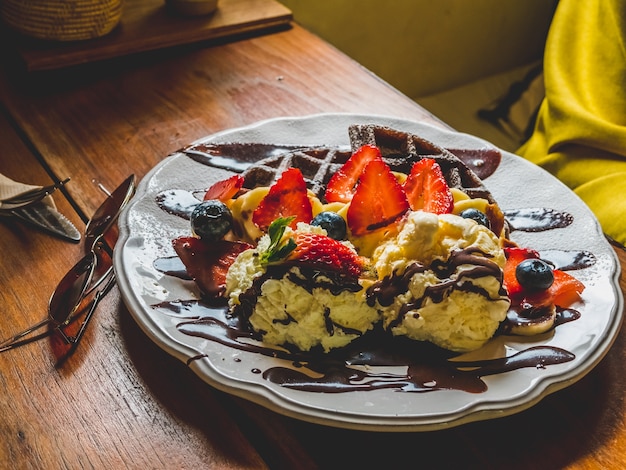 Foto pancakes al cioccolato con banana, fragola, mirtillo, gelato, brownies e cioccolato.