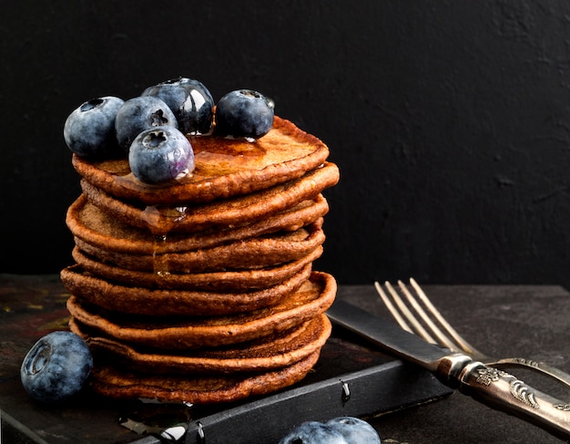 Pancake al cioccolato con mirtilli su uno sfondo scuro.