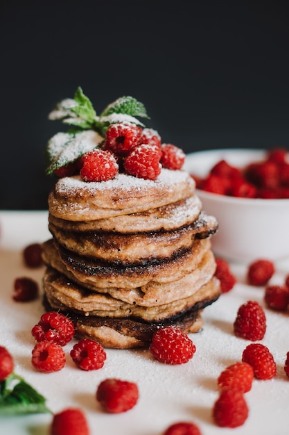 Pancake al cioccolato con lamponi freschi e menta su sfondo nero