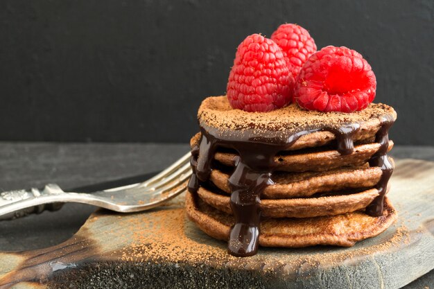 Chocolate pancakes with raspberry on a dark background.